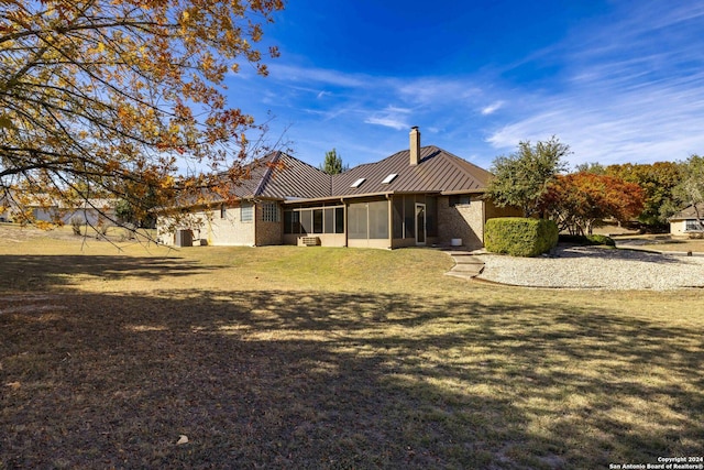 back of house with a sunroom and a lawn