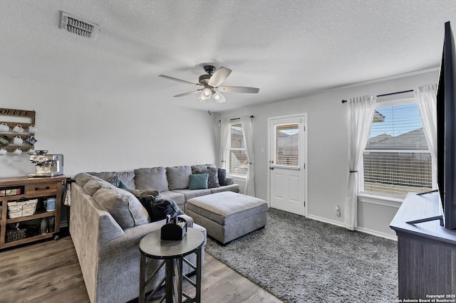 living room with ceiling fan, dark hardwood / wood-style floors, and a textured ceiling