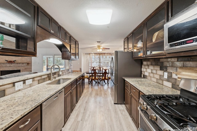 kitchen featuring stainless steel appliances, light stone countertops, sink, and dark brown cabinets