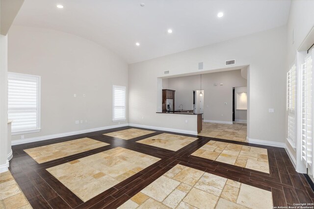 unfurnished living room featuring sink and high vaulted ceiling