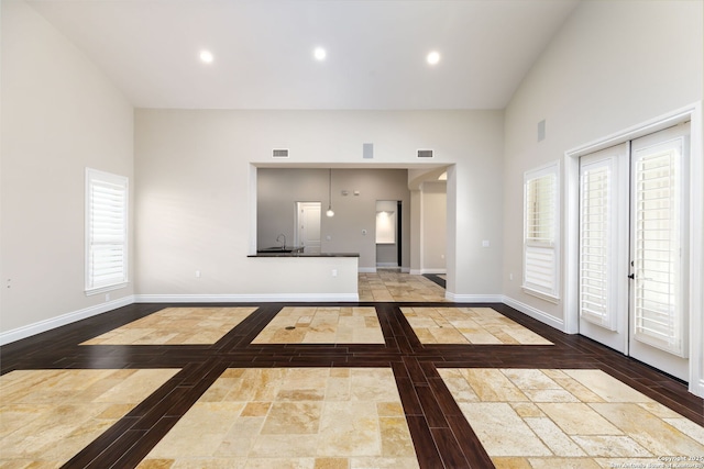 unfurnished living room with sink, high vaulted ceiling, and french doors