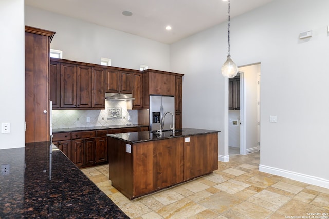 kitchen with sink, pendant lighting, stainless steel fridge, and dark stone counters