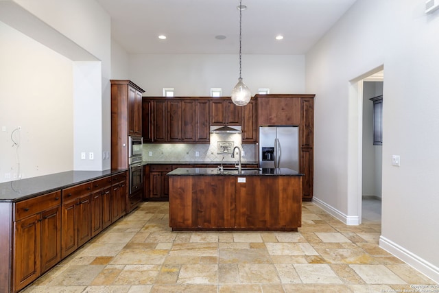 kitchen with pendant lighting, sink, appliances with stainless steel finishes, dark stone countertops, and decorative backsplash