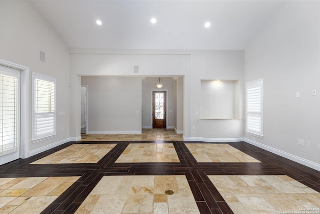 foyer entrance with wood-type flooring, high vaulted ceiling, and a wealth of natural light