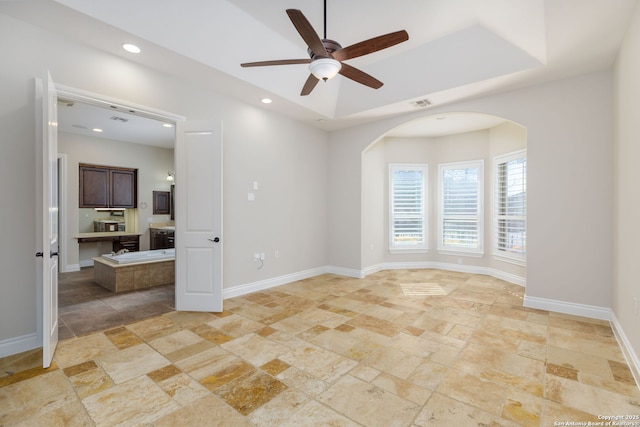 unfurnished room featuring a raised ceiling and ceiling fan