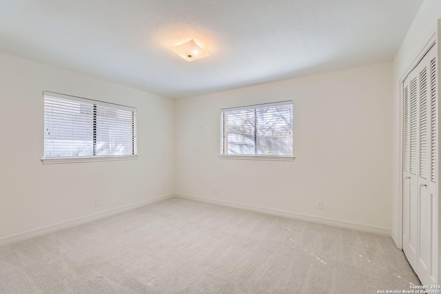 unfurnished bedroom with light colored carpet and a closet