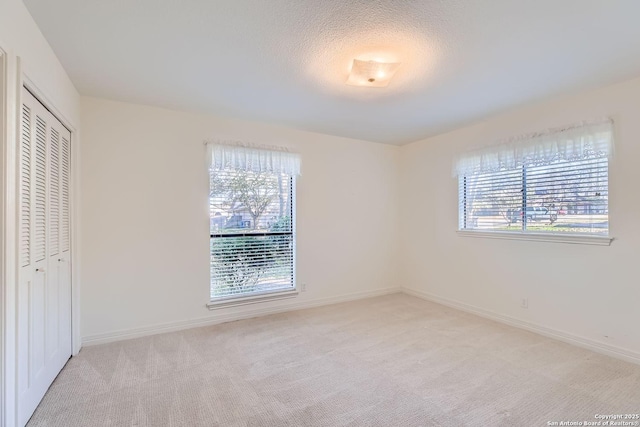 unfurnished bedroom with light colored carpet, a textured ceiling, and a closet