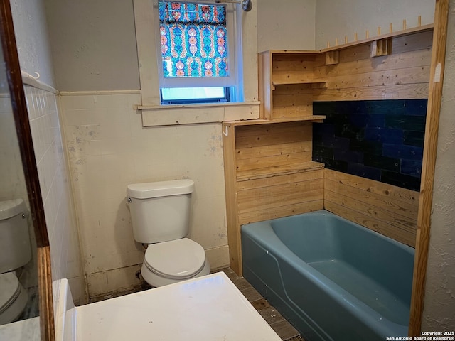 bathroom featuring tile walls, toilet, and a bathing tub