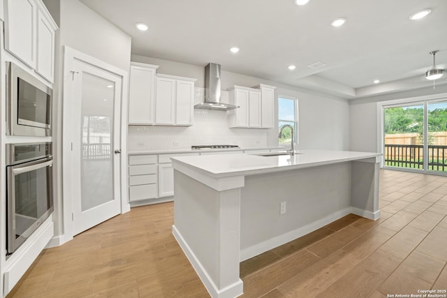 211 Ryan Xing, San Antonio, TX 78253 - kitchen with wall chimney range hood, stainless steel appliances, a sink, a center island with sink, and light countertops