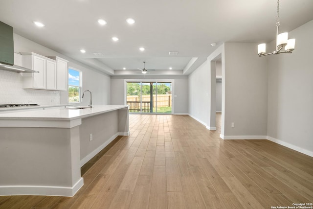 211 Ryan Xing, San Antonio, TX 78253 - kitchen featuring wall chimney exhaust hood, light countertops, open floor plan, a chandelier, and light wood-type flooring