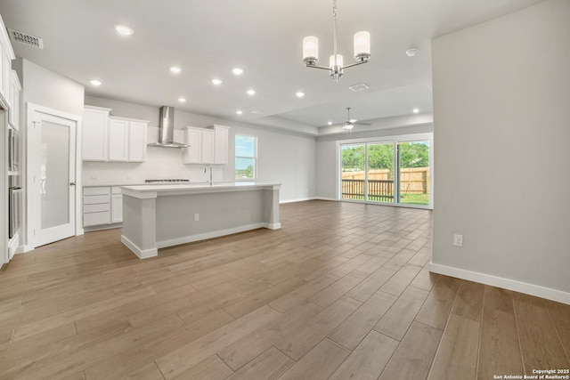 211 Ryan Xing, San Antonio, TX 78253 - kitchen featuring wall chimney range hood, open floor plan, a ceiling fan, light wood-style floors, and white cabinets