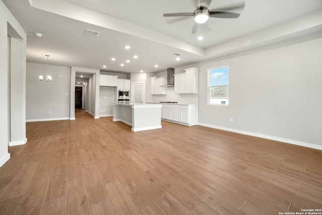 211 Ryan Xing, San Antonio, TX 78253 - unfurnished living room with a sink, ceiling fan, light wood finished floors, baseboards, and a chandelier