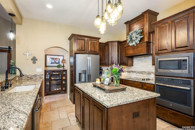 kitchen with stainless steel appliances, stone tile flooring, decorative light fixtures, and a sink