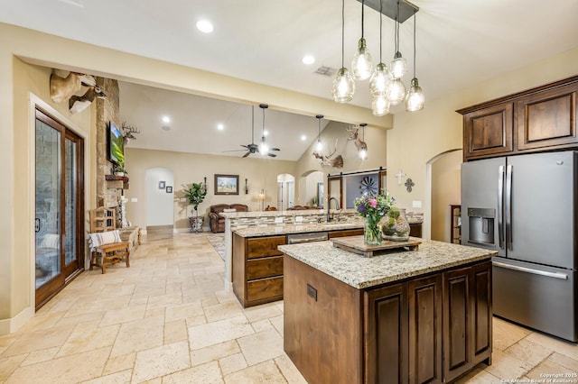 kitchen featuring arched walkways, stone tile flooring, and stainless steel refrigerator with ice dispenser