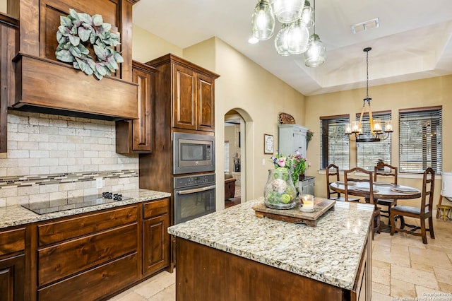 kitchen featuring stone tile floors, visible vents, appliances with stainless steel finishes, a center island, and tasteful backsplash