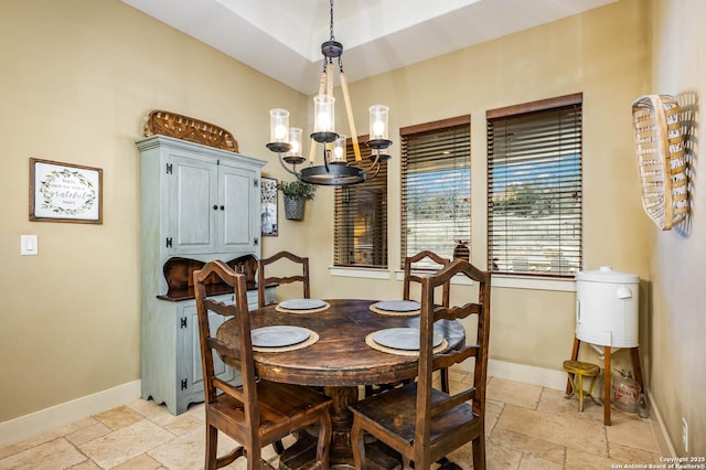 dining space featuring a chandelier, baseboards, and stone tile floors