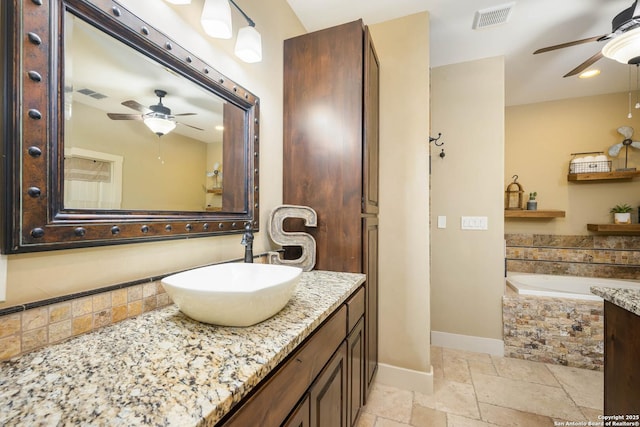 bathroom with a garden tub, stone tile flooring, vanity, and visible vents