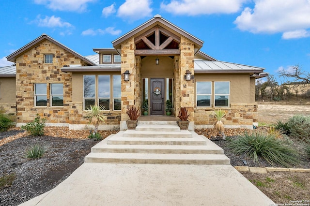 view of front of home with stone siding, a standing seam roof, metal roof, and stucco siding