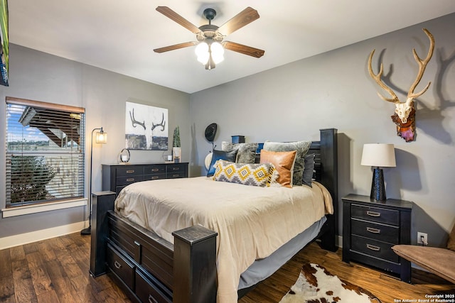 bedroom with dark wood-style floors, a ceiling fan, and baseboards