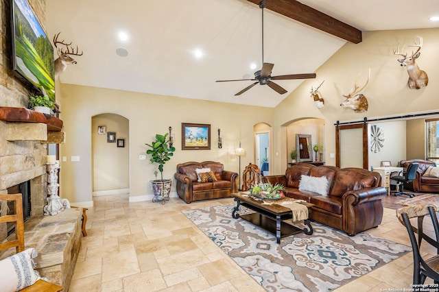 living room featuring a barn door, arched walkways, stone tile floors, and beamed ceiling