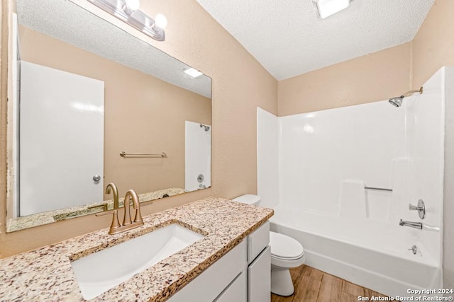 full bathroom with toilet, wood-type flooring,  shower combination, a textured ceiling, and vanity