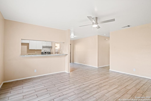 unfurnished living room featuring ceiling fan and light wood-type flooring