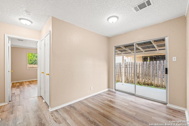 unfurnished room with light hardwood / wood-style floors and a textured ceiling