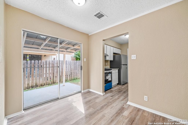 empty room with light hardwood / wood-style flooring and a textured ceiling