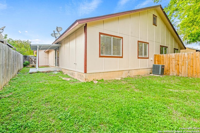 view of side of home featuring cooling unit, a lawn, and a patio area