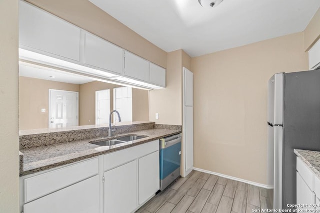 kitchen with stainless steel appliances, stone countertops, sink, and white cabinets