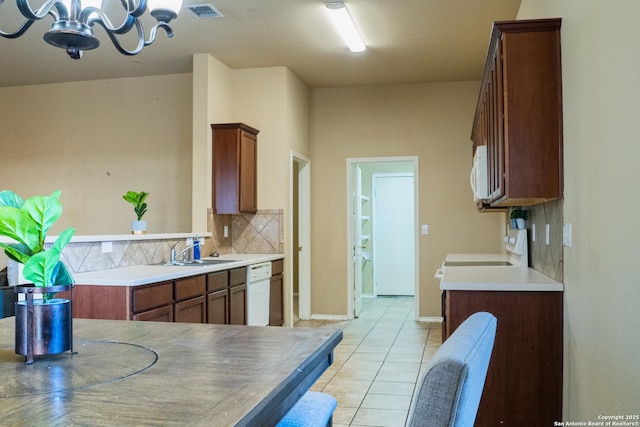 kitchen featuring sink, tasteful backsplash, an inviting chandelier, light tile patterned floors, and white appliances