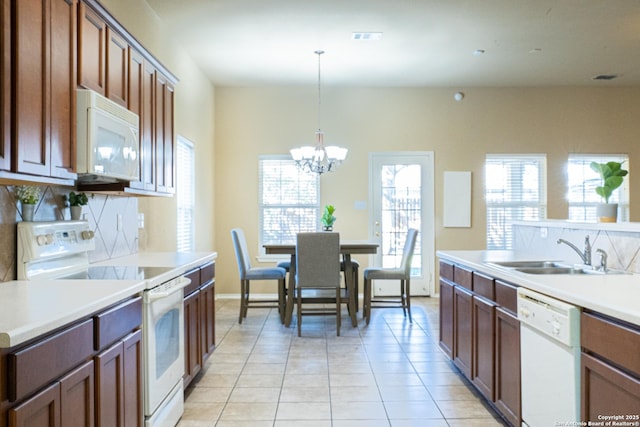 kitchen with sink, an inviting chandelier, hanging light fixtures, light tile patterned floors, and white appliances