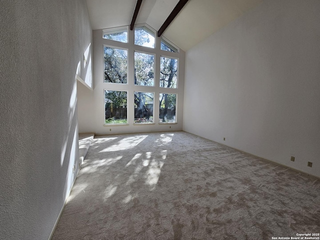 unfurnished living room featuring high vaulted ceiling, carpet floors, and beam ceiling