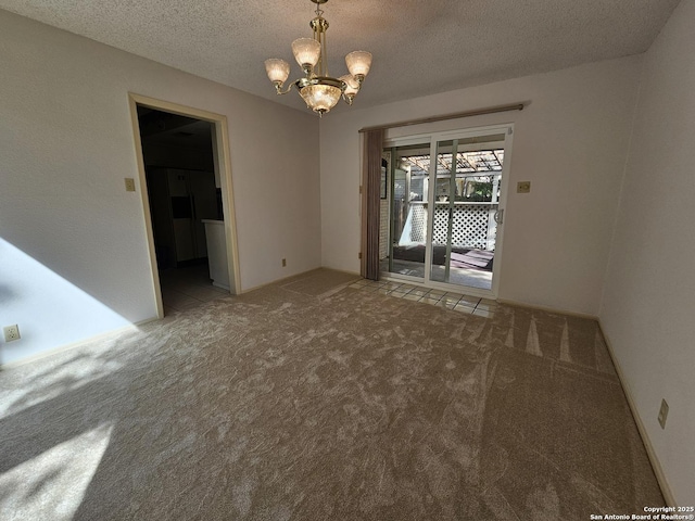 carpeted spare room with a chandelier and a textured ceiling