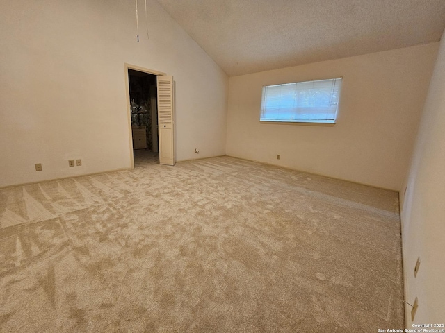 spare room featuring lofted ceiling, light colored carpet, and a textured ceiling