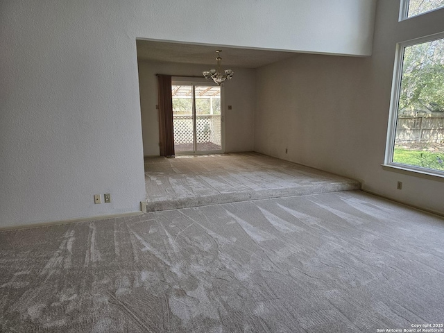 empty room featuring light carpet and an inviting chandelier