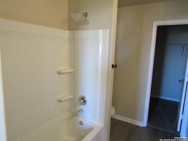 bathroom featuring hardwood / wood-style flooring, shower / washtub combination, and toilet