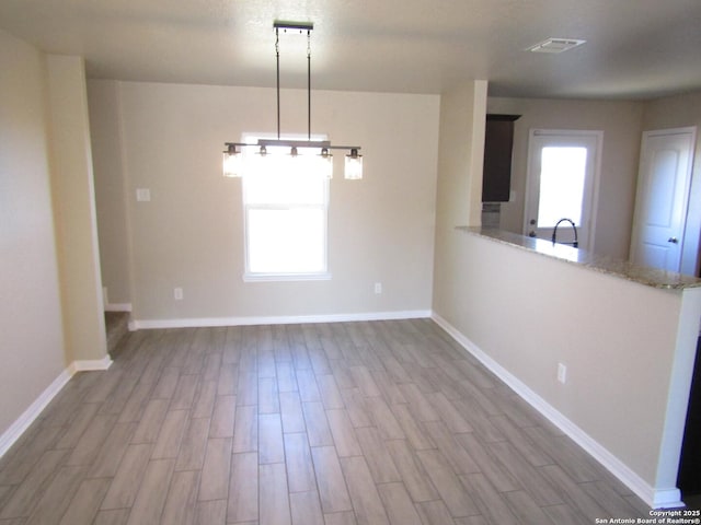 unfurnished dining area featuring plenty of natural light, sink, and light wood-type flooring