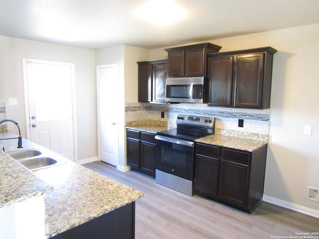 kitchen with tasteful backsplash, appliances with stainless steel finishes, sink, and light hardwood / wood-style floors