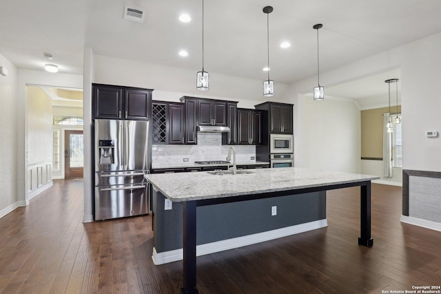 kitchen with appliances with stainless steel finishes, a kitchen bar, and hanging light fixtures