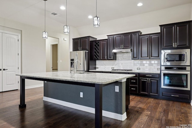 kitchen with hanging light fixtures, a breakfast bar, an island with sink, and appliances with stainless steel finishes