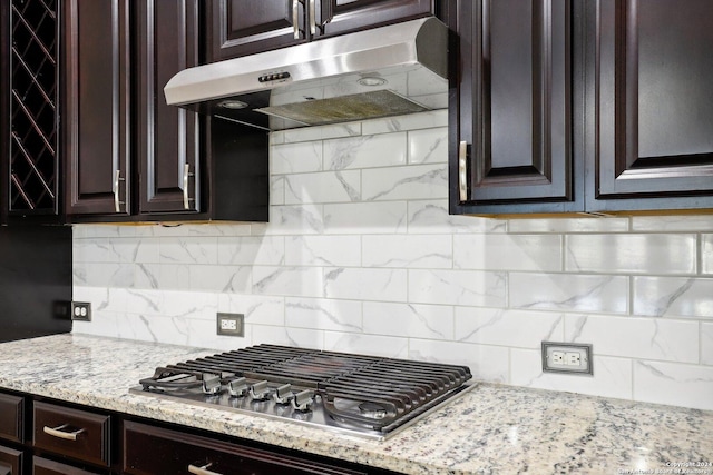 kitchen with tasteful backsplash, light stone counters, dark brown cabinets, and stainless steel gas stovetop