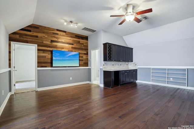 unfurnished living room featuring lofted ceiling, dark hardwood / wood-style floors, and wood walls