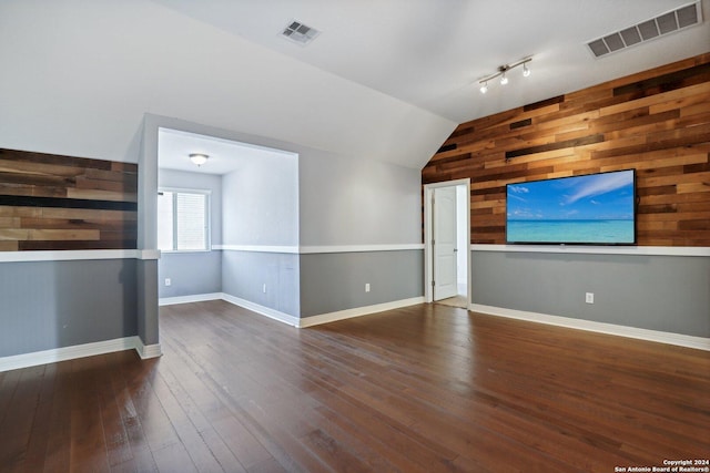 unfurnished living room with lofted ceiling, dark hardwood / wood-style floors, and wood walls