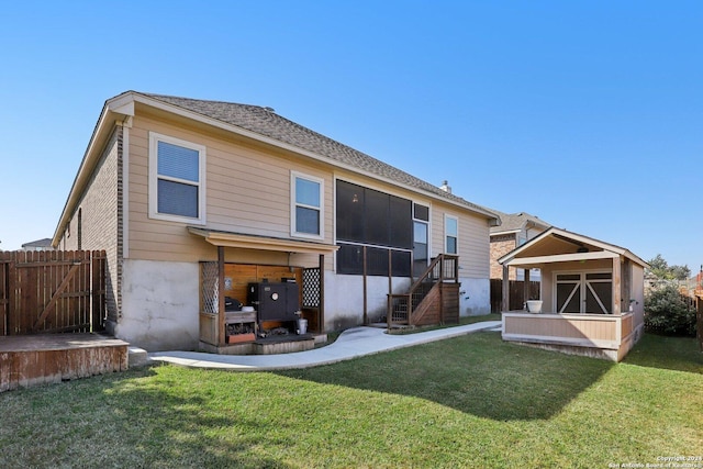 rear view of house featuring a sunroom and a yard