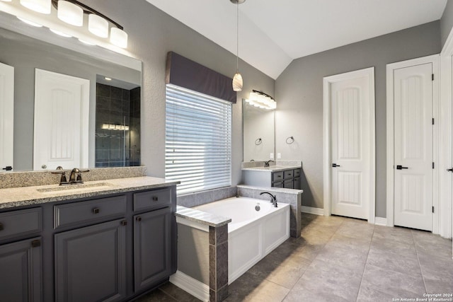 bathroom featuring tile patterned floors, vanity, vaulted ceiling, and a washtub