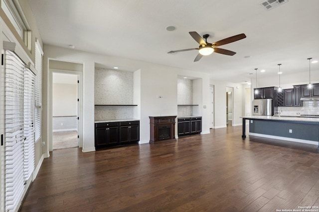 unfurnished living room featuring sink, dark wood-type flooring, and ceiling fan