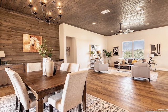 dining area with wood ceiling, wood walls, ceiling fan with notable chandelier, and light wood-type flooring