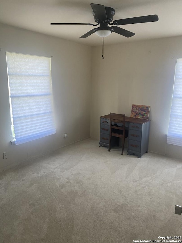 unfurnished office with plenty of natural light, light colored carpet, and ceiling fan