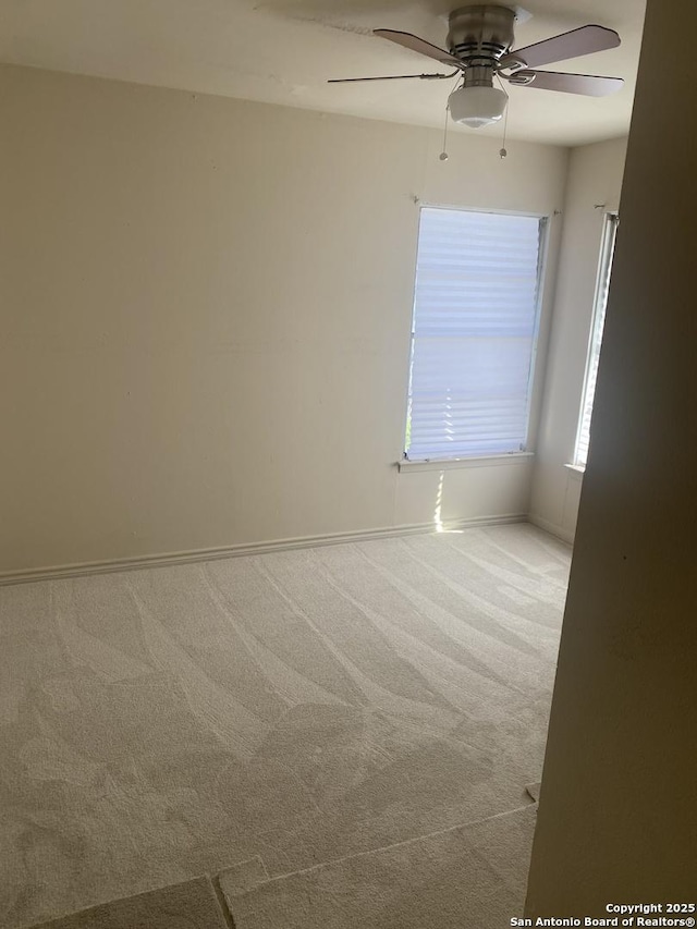 carpeted spare room featuring ceiling fan